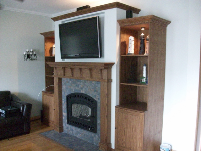 Cozy heat producing Wood Burning Fireplace with Black Wrought Arch Front Glass Door,2" Earth Slate Tile Surround and Hearth, Lighted Book Case and Cabinets in a Mission Style with Hand Rubbed Early American Finish.