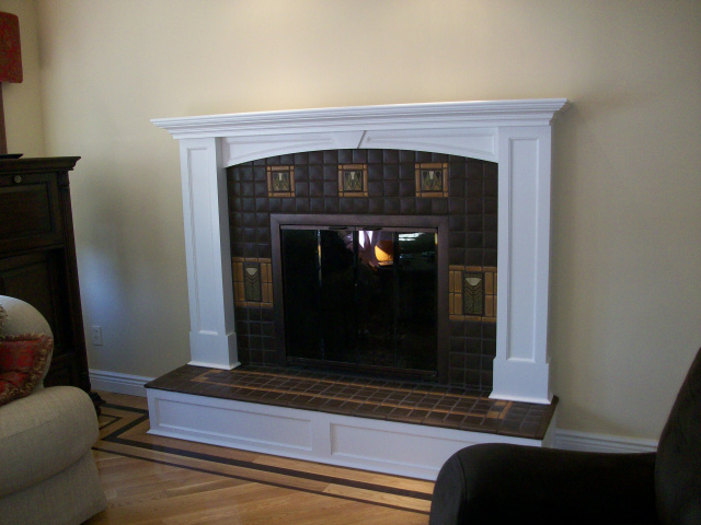 Custom hand made Motawi tile surround with bordered flower features and hearth extention design. Custom finished arched woodwork mantel and riser.