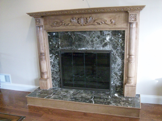 Raised hearth extention with dark empradore marble surround, maple mantel finished in natural cherry. custom glass door in textured chestnut finish.