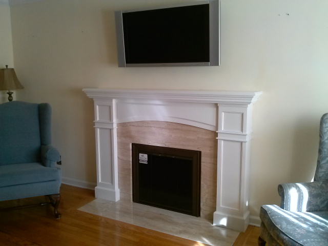 Formalized living room fireplace with Diana Realle marble surround and hearth extention, custom arched white mantel, new 3" oak hearth moulding and custom inside fit full swing bifold glass doors in fine textured brown with bronze glass.