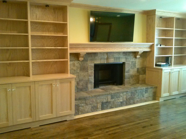 Bright and functional wood burning makeover has enlarged opening with custom hanging screens, european castle stone, custom red oak mantel, crown mouldings around room, lighted built-ins with cut glass knobs, adjustable shelving, media hookups and even a floor refinishing.
