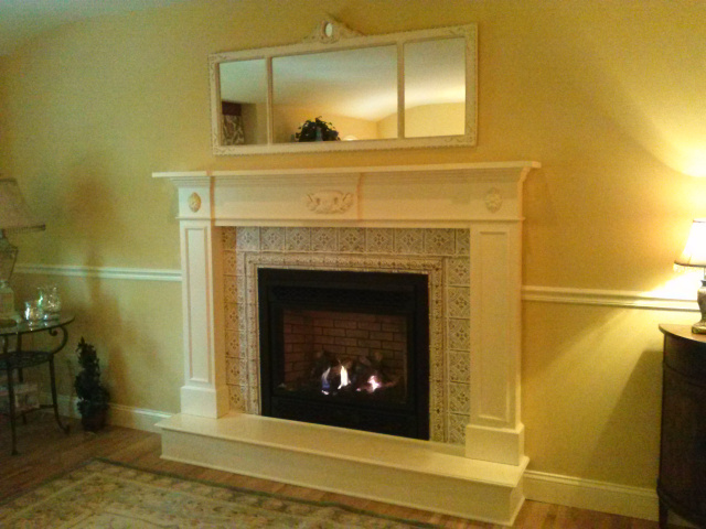 Living Room Gas Fireplace brought into alignment with the taste and sensitivities of the rooms personality with a new firebox, metal art firebox surround and custom designed painted mantel with hearth extention.